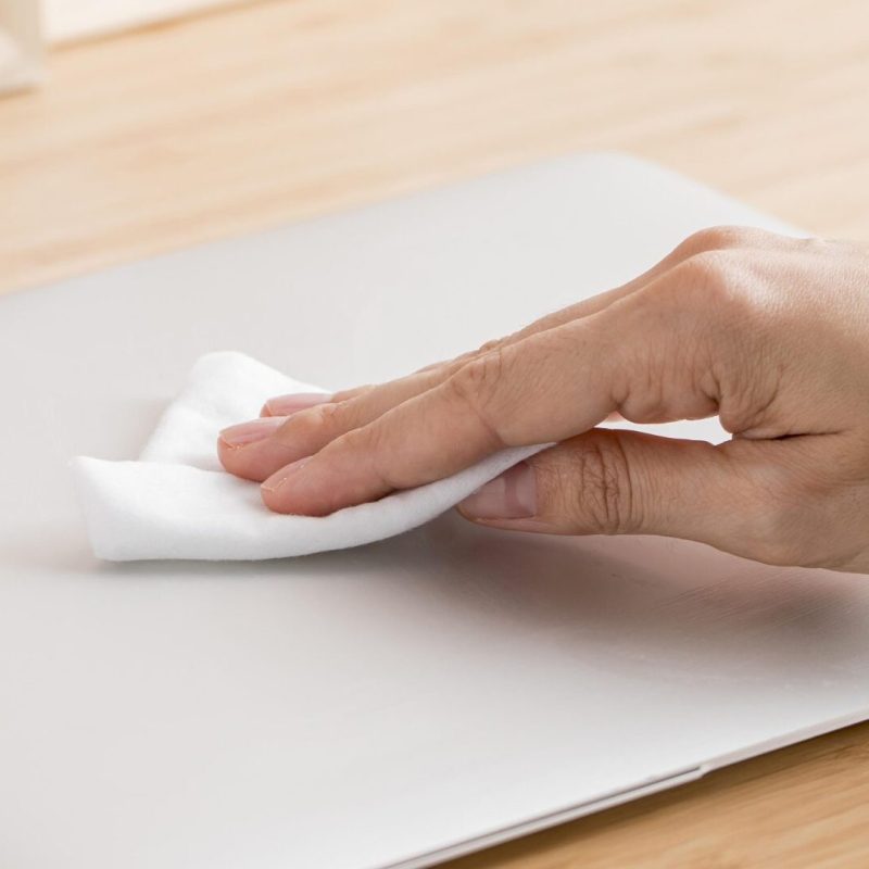 high-angle-hand-disinfecting-laptop-desk